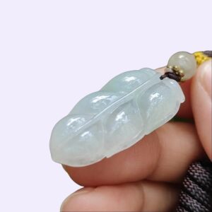 une main tenant un pendentif en jade