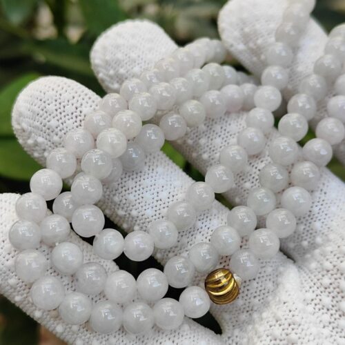 a hand wearing white glove with a string of beads