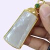 a hand holding a jade pendant
