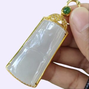 a hand holding a jade pendant