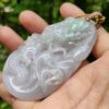 a hand holding a jade pendant