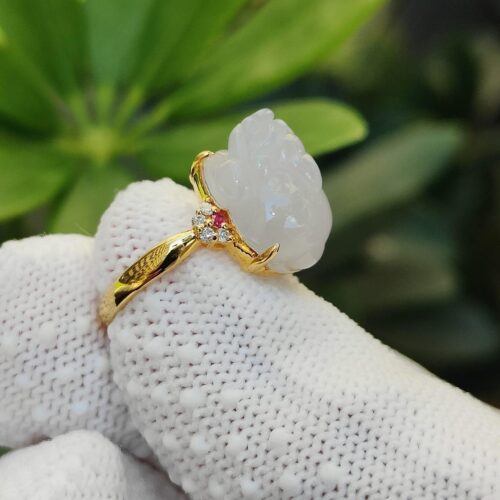 a hand wearing a gloved hand holding a white ring with a carved stone