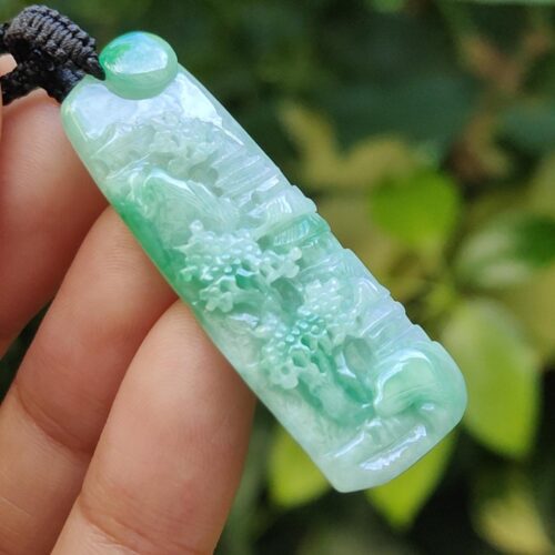 a hand holding a jade pendant
