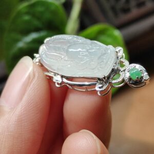 tangan memegang cincin perak dengan batu giok