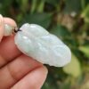 a hand holding a jade leaf pendant
