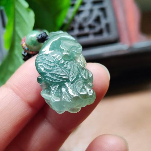 tangan memegang liontin giok