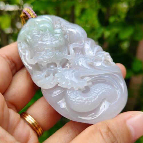 a hand holding a jade pendant