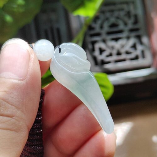 a hand holding a jade pendant