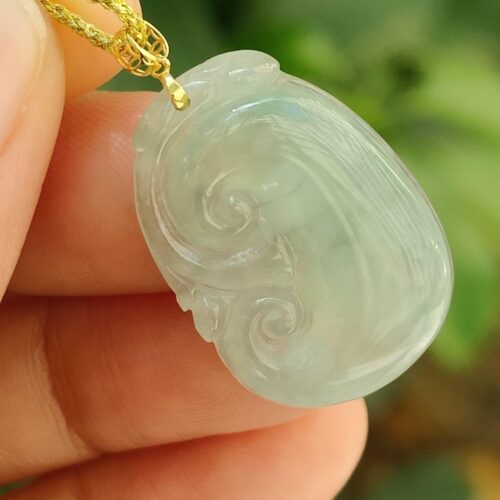 một bàn tay cầm một mặt dây chuyền ngọc bích