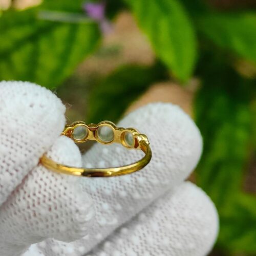 a hand wearing a glove holding a gold ring