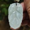 a hand holding a white jade pendant