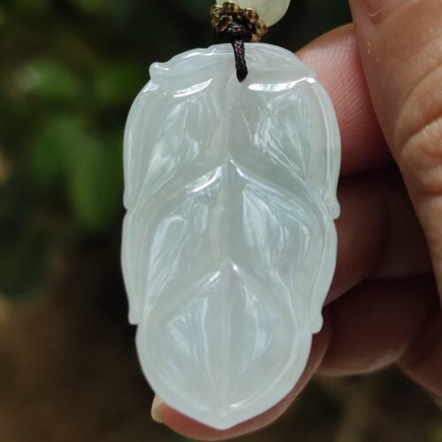 a hand holding a white jade pendant