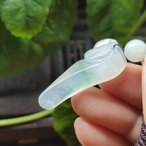 a hand holding a jade pendant