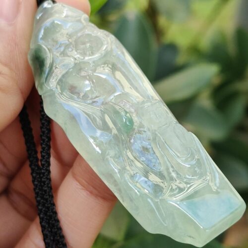 a hand holding a jade pendant
