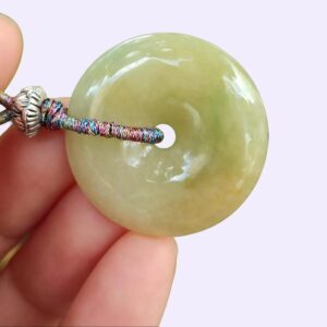 a hand holding a jade pendant