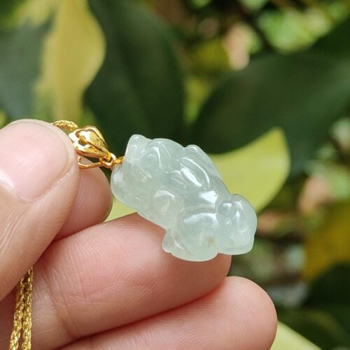 une main tenant un pendentif en jade