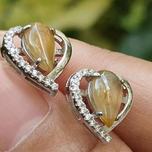 a person's hand holding a pair of earrings