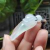a hand holding a jade pendant