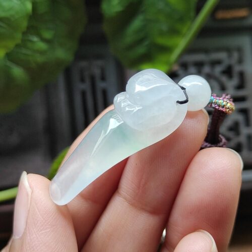 a hand holding a jade pendant