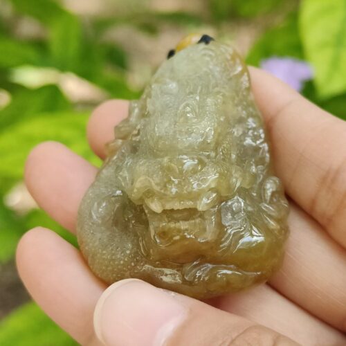 a hand holding a small green creature