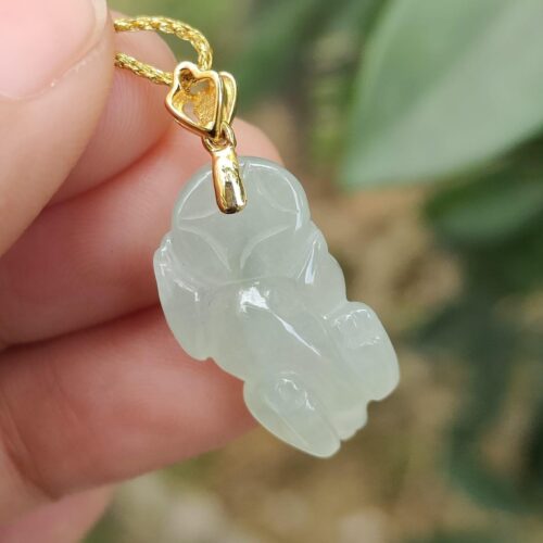 une main tenant un pendentif en jade