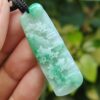 a hand holding a jade pendant