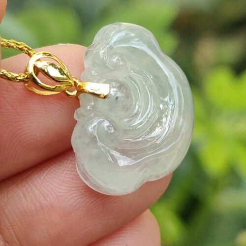 a hand holding a jade pendant