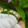 a hand holding a gold ring with pearls on it