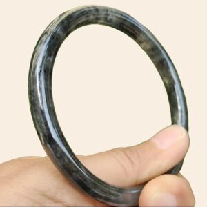 a hand holding a round black and grey ring