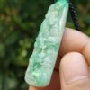 a hand holding a jade pendant