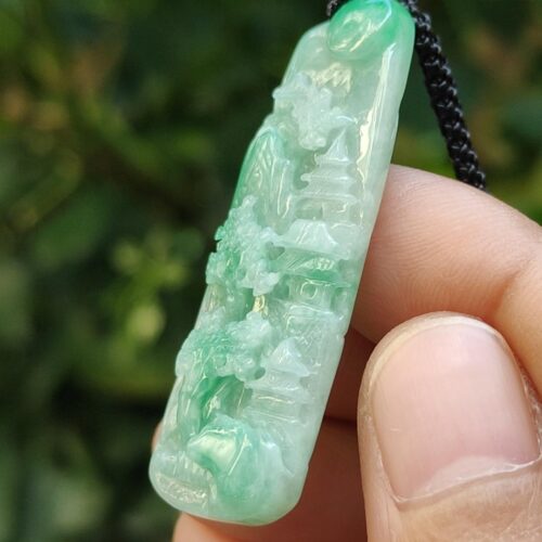 a hand holding a jade pendant