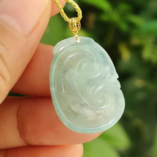 một bàn tay cầm một mặt dây chuyền ngọc bích