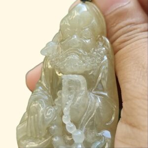 a hand holding a jade pendant