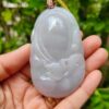 a hand holding a jade pendant