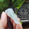 a hand holding a jade pendant