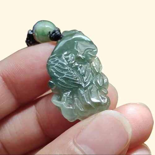 tangan memegang liontin giok