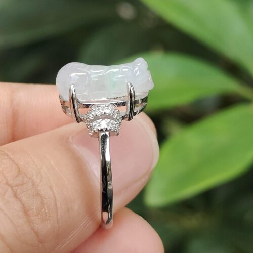 a hand holding a ring with a jade stone on it