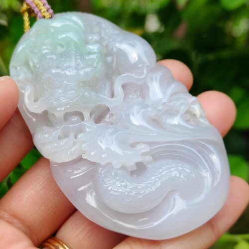 a hand holding a jade pendant