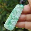 a hand holding a jade pendant