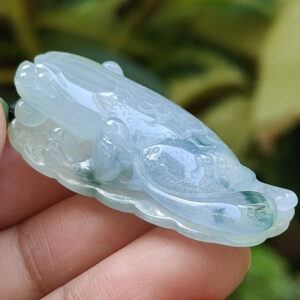 une main tenant un pendentif grenouille en jade