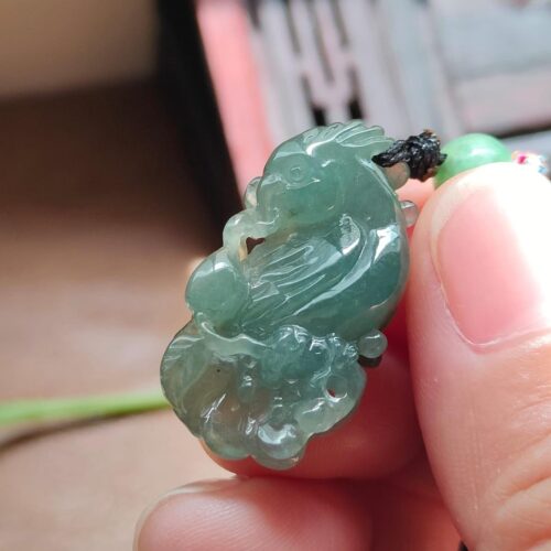 tangan memegang liontin giok