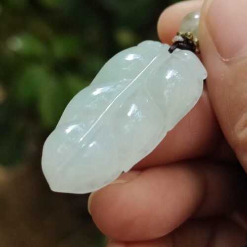 a hand holding a jade pendant
