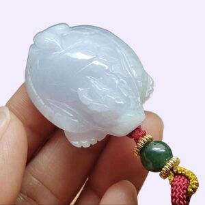 a hand holding a jade pendant
