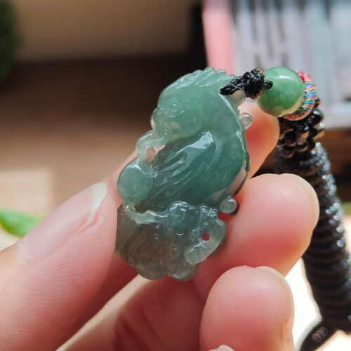 tangan memegang liontin giok