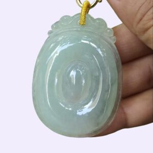 a hand holding a jade pendant