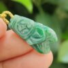 a hand holding a jade pendant - Cicada