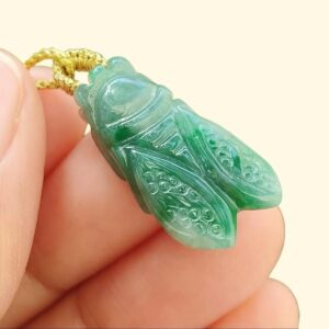 uma mão segurando um pingente de inseto verde - Cicada