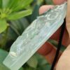 a hand holding a jade pendant