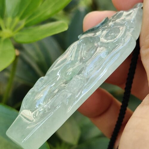 a hand holding a jade pendant