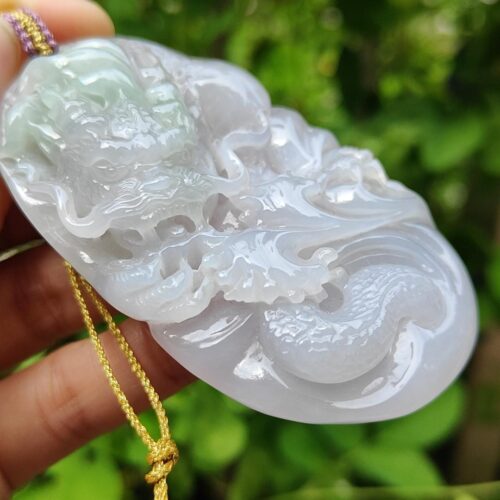 a hand holding a jade pendant